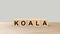 Koala - word wooden cubes on table horizontal over gray background. Australia animal, australian emergency, help fire emblem