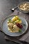 Koenigsberger Klopse or boiled meatballs in a white bechamel sauce with capers, potatoes and beetroot on a blue plate, dark gray