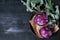 Kohlrabi cabbage with green tops leaves on a metal plate with a pair of scissors on a white textile on a black vintage wooden back