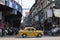 Kolkata, India - February 1, 2020: Unidentified people stands and walks on the street as a traditional yellow taxi drives by