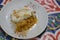 Konafa topped with whipped cream, raisins, walnuts, shredded coconut and stuffed with cream and fresh mango layer and soaked with