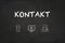 `Kontakt` text and icons on a blackboard. Translation: `Contact`