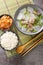 Korean Beef Radish Soup Sogogi Muguk served with rice and kimchi closeup on the mat. Vertical top view