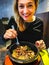 Korean bibimbap served in hot stone dolsot pot bowl eaten by caucasian smiling woman dining in korean ethnic restaurant