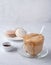 Korean dalgona coffee flow in a glass Cup with macaroon and instant coffee on light gray  background. Trendy  drink