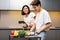 Korean Family Couple Cooking Healthy Food Standing In Modern Kitchen