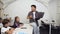 Korean male teacher sitting on the desk with laptop in hand giving lesson for pupils. Schoolchildren listening carefully