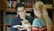 Korean man in glasses with a woman talking in the library.