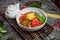 Korean noodle with kimchi, tomatoes, chili in white bowl on bamboo tray with tea pot