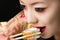 Korean teenager girl with bright makeup eating sushi closeup
