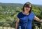 Korean tourist atop the Tourrettes sur Loup in Provence, France, with bridge for cars and countryside in the background.