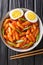 Korean tteokbokki spicy rice cake with eggs close-up in a bowl. Vertical top view