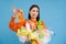 Korean woman looks at stinky latex glove, holds plastic garbage, cleans house and recycle, blue background