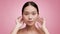 Korean Woman Making Facial Massage Stroking Face On Pink Background