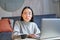 Korean woman with perplexed face, sitting with laptop, working on remote, freelancer with confused expression looking at