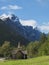 Kors Church, old wooden parish church in Rauma in Romsdal valley, Norway with road E136, green forest and mountain massif