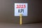 KPI, key performance indicator symbol. White paper with words KPI 2023, clip on wooden clothespin. Beautiful grey table grey