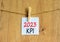 KPI, key performance indicator symbol. White paper with words KPI 2023, clip on wooden clothespin. Beautiful wooden background.
