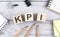 KPI text on wooden block with office tools on the wooden background