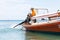 Krabi, Thailand - February 12, 2019: The driver of a longtail motorboat drives a motor with a long drive and a propeller. Sailor