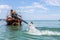 Krabi, Thailand - February 12, 2019: The driver of a longtail motorboat drives a motor with a long drive and a propeller. Sailor