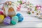 Kulich, traditional Russian Ukrainian Easter cake with icing and colored eggs with lace ribbon on white wooden background with flo