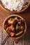 Kung pao chicken in a bowl close up and rice. vertical top view