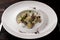 kurze dish on a plate, with a fork and a knife on a wooden background with spices