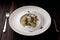 kurze dish on a plate, with a fork and a knife on a wooden background with spices