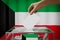 Kuwait flag, hand dropping ballot card into a box - voting, election concept