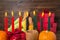 Kwanzaa festive concept with burning candles, gift box, pumpkins, ears of wheat, grapes, corns, banana, bowl and fruits on wooden