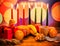 Kwanzaa festive concept with seven candles red, black and green, gift box, pumpkin, bowl and fruit on light blur bokeh background