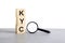 KYC - Know Your Client - text wooden cube blocks and magnifying glass on grey table