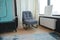 KYIV, UKRAINE - August, 07, 2023: Gray modern compact armchair for small spaces near the large window with radiator heater