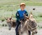 Kyrgyz kid riding a donkey through the countryside