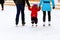 A l boy with dad and mom skates on the rink in the winter. Active family sport, winter holidays, sports clubs
