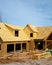 L shaped wooden house with gabled dormer roof under construction, oriented strand board (O