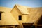 L shaped wooden house with gabled dormer roof under construction, oriented strand board (OSB) plyw