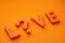 L...ve word is laid out in orange letters on an orange background. question Love or Live