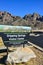 `La Cueva Trailhead` information sign against a mountain landscape with cacti, New Mexico