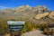 `La Cueva Trailhead` information sign against a mountain landscape with cacti, New Mexico