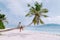 La Digue Seychelles, sunset on the white tropical beach with palm tree, young woman on vacation at the Seychelles