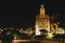 La Torre de Oro in Seville, Spain at night brightly lit by the river