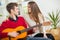 LA young and attractive couple sitting on a couch with a guitar.