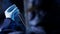 Lab assistant in protective suit studying sample in laboratory glass tube cuvette. Close up selective focus