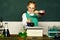 Lab microscope and testing tubes. Child in the class room with blackboard on background. Biology experiments with