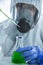 Lab technician holding dropper with dripping in flask. Scientist in personal protective equipment suit are working and analyzed