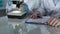 Lab worker filling paper forms, his assistant viewing samples under microscope