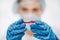 Lab worker in rubber gloves holding red medicine to cure coronavirus in clinic