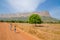 Labe, Guinea - December 20, 2013: Two unidentified boys walking on dirt road looking back with tree and mountain